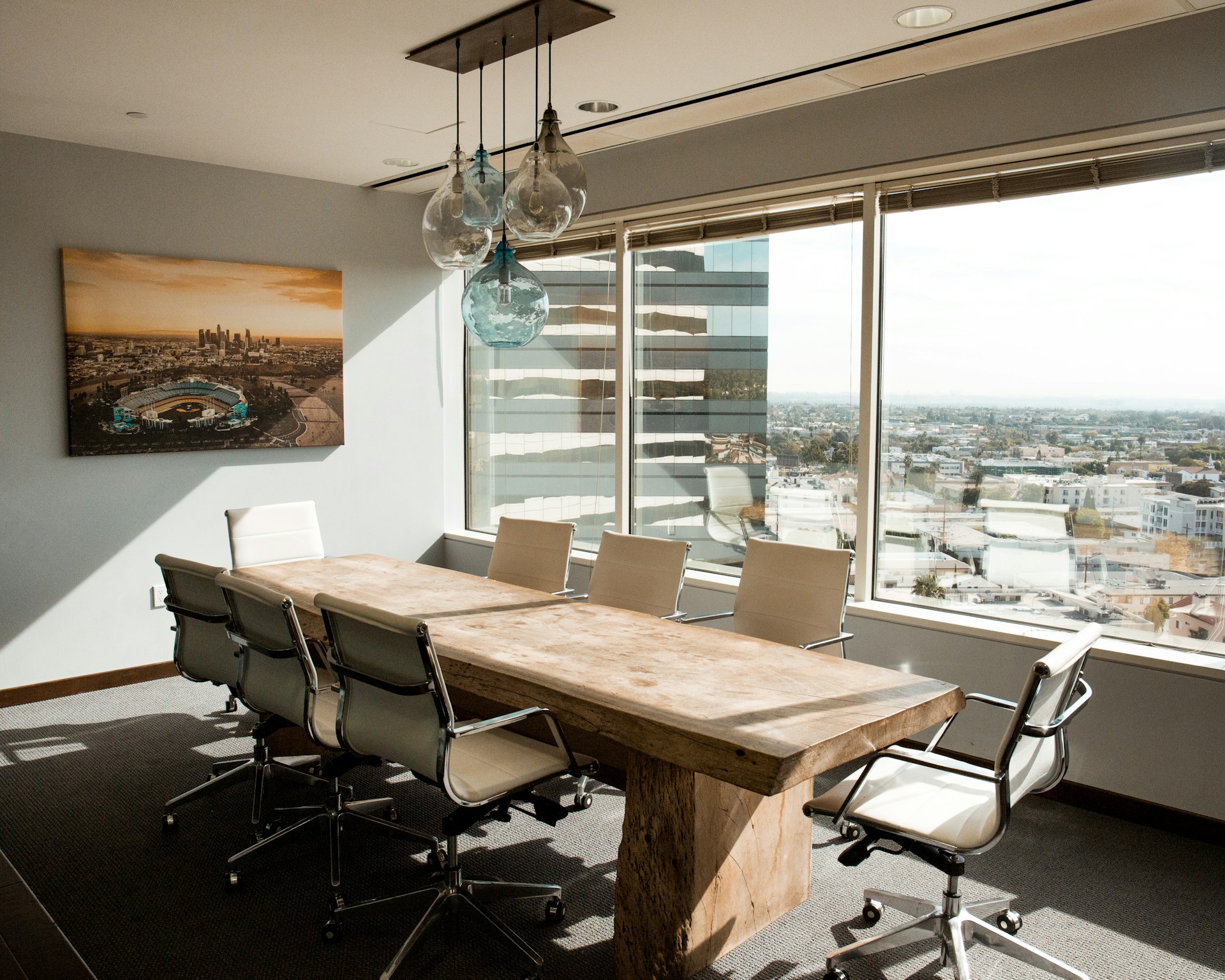 Sunlit executive boardroom with a long wooden table and city view